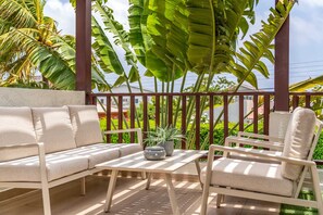 A covered outdoor seating area with a sofa and chairs, a table, and a potted plant. - PB98B-3 - Private Villa with pool - Close to Palm Beach (Palm Beach)
