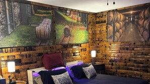 Een slaapkamer met een houten hoofdbord, een bed met blauw beddengoed, twee nachtkastjes met lampen en een plafondventilator.