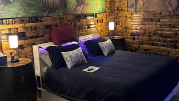 Een slaapkamer met een houten hoofdbord, een bed met blauw beddengoed, twee nachtkastjes met lampen en een plafondventilator.