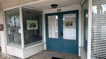 A building entrance with a blue door, numbered 205, and a black doormat.