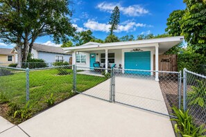 A residential property with a fenced yard, a covered porch, and a garage.