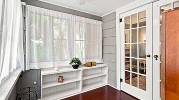 A room with a large window, a white door with glass panels, and a built-in bench with shelves.