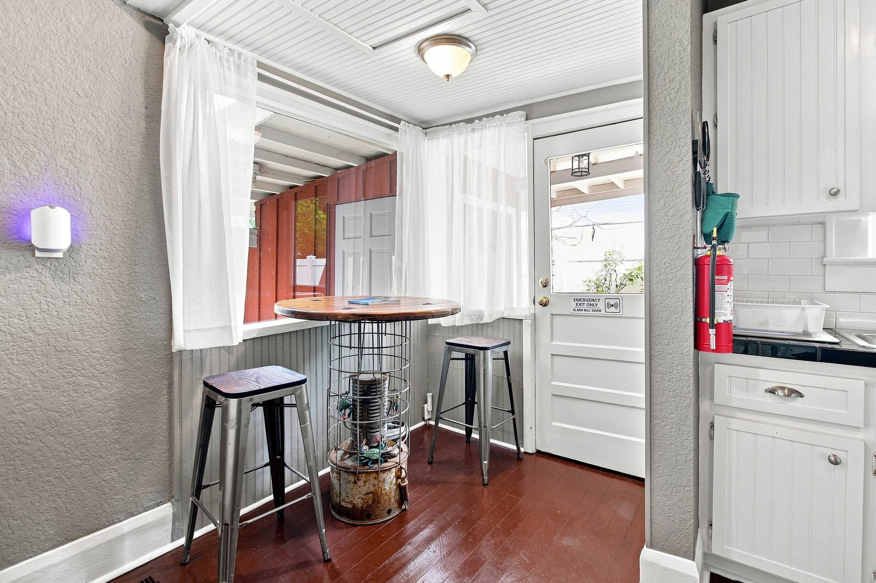A small kitchen with a bar area, a fire extinguisher, and a window with curtains.