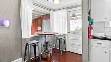 A small kitchen with a bar area, a fire extinguisher, and a window with curtains.