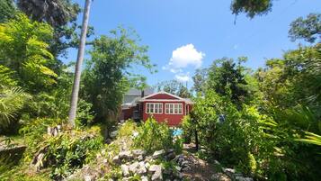 A red house surrounded by lush greenery and a clear blue sky.