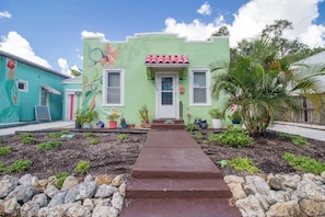 A colorful house with a green facade, a red-tiled roof, and a front door with a small porch. - The Koi House Cottage (Bradenton)