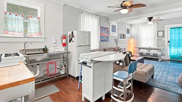 A compact living space with a kitchenette, a dining area, and a seating area with a blue patterned rug.