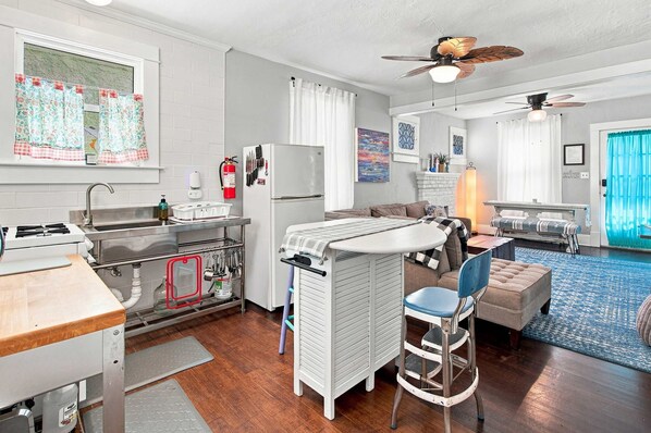 A compact living space with a kitchenette, a dining area, and a seating area with a blue patterned rug.