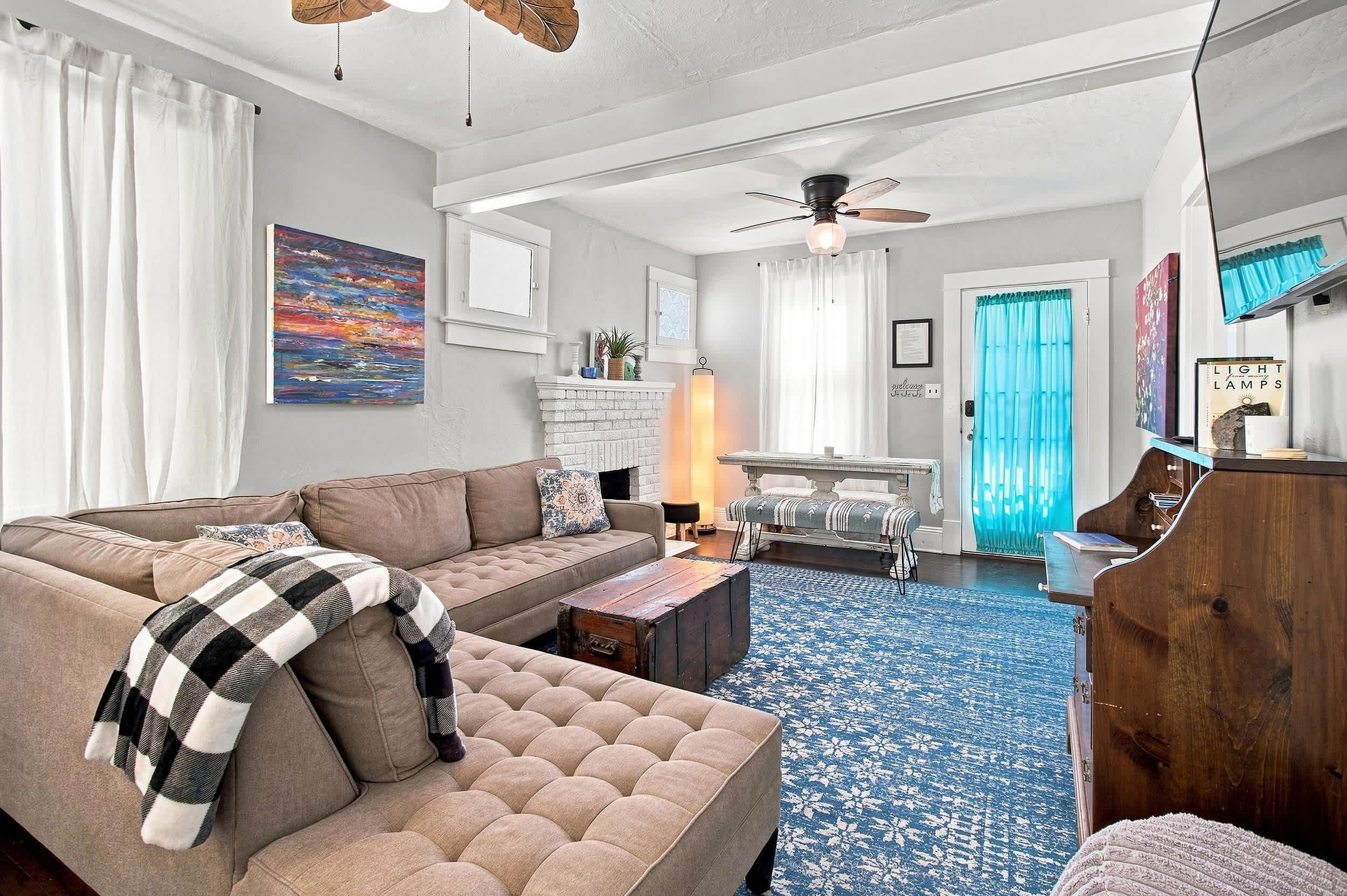 A living room with a sofa, a coffee table, and a fireplace. There is a dining table with chairs in the background.
