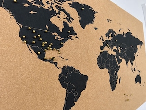 Une carte du monde avec des punaises dorées indiquant des lieux précis.