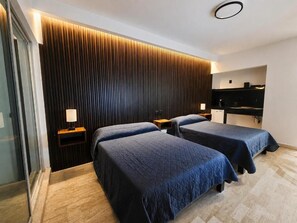 Quarto de hotel com duas camas, cabeceira de ripas de madeira, abajures, TV de tela plana e mesa de cabeceira de madeira.