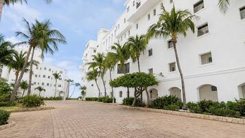 Um hotel com vários andares, pátio pavimentado e palmeiras.