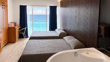 Ein Hotelzimmer mit zwei Betten, einer großen Badewanne und Meerblick.