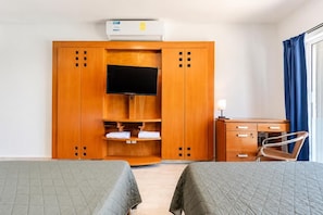 A hotel room with two beds, a wardrobe, a desk, a chair, and a television. - Suites Sol y Luna (Cancún)