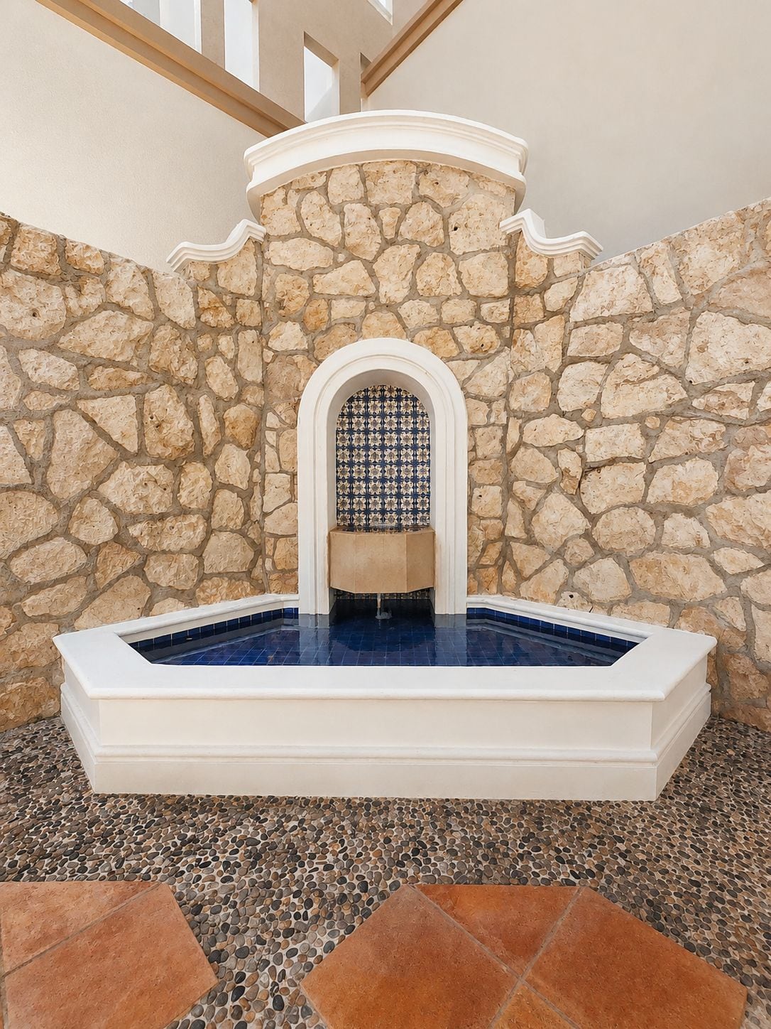 Un muro de piedra con un arcoado de azulejos que da paso a una zona de hidromasaje.