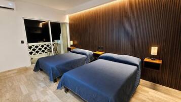 A hotel room with two beds, a wooden wall paneling, and a view of a balcony.