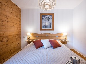 Ein Hotelzimmer mit einem hölzernen Kopfteil, einem Bett mit gesteppter Matratze, zwei Nachttischlampen, einem gerahmten Bild an der Wand und einem Wasserkocher auf dem Beistelltisch.