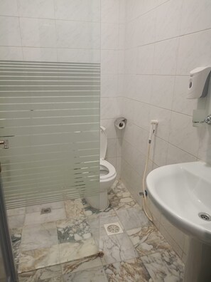 Ein Badezimmer mit Toilette, Waschbecken und einer Duschabtrennung aus Glas.