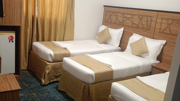 Habitación de hotel con dos camas, cabecera de madera, piso alfombrado y aire acondicionado.