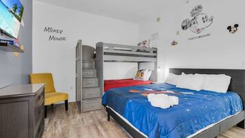 A room with a bunk bed, a desk, a chair, and wall decorations including Mickey Mouse.