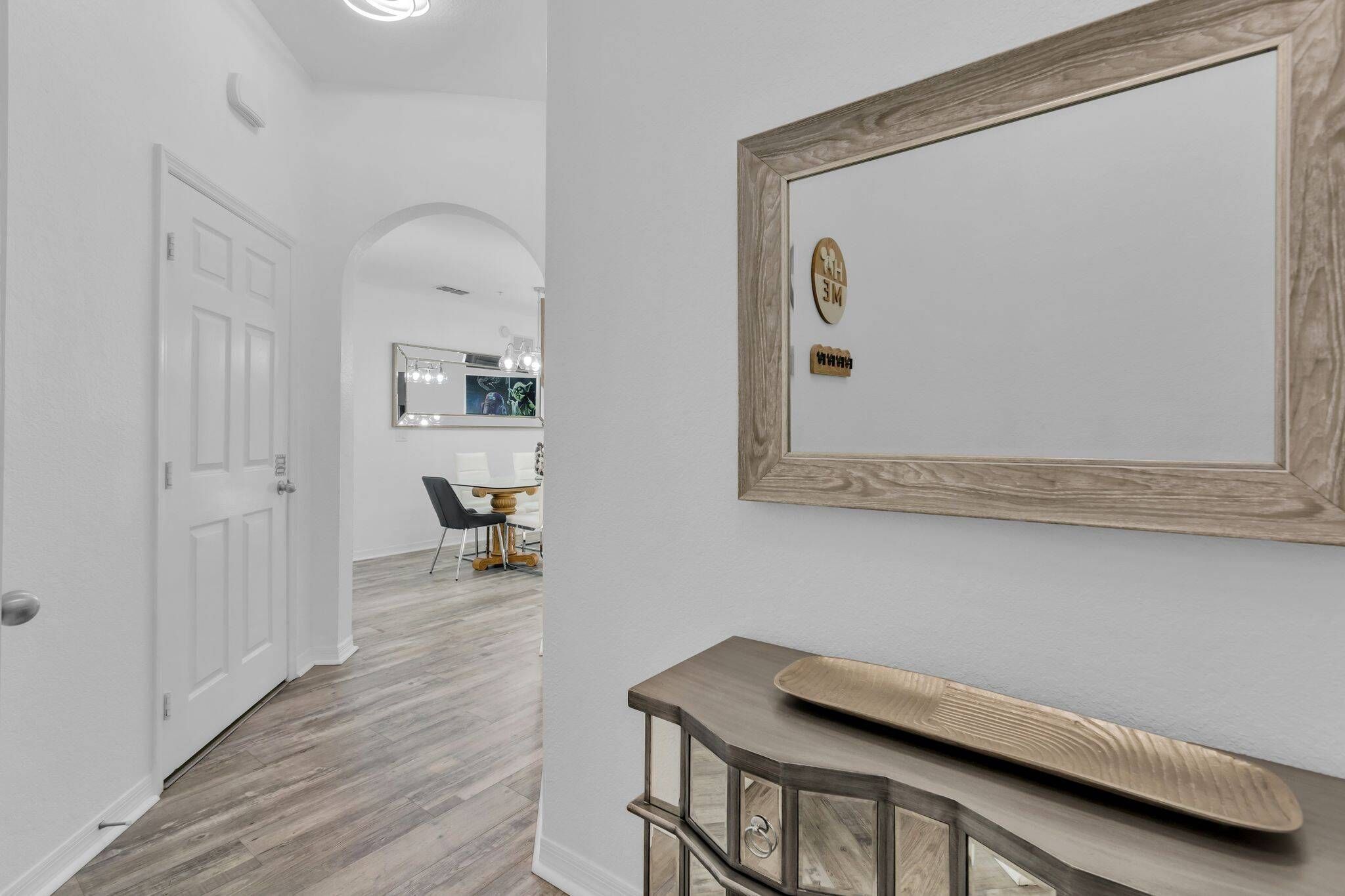 A hallway with a white door, a mirror, and a wooden console table with a decorative object.