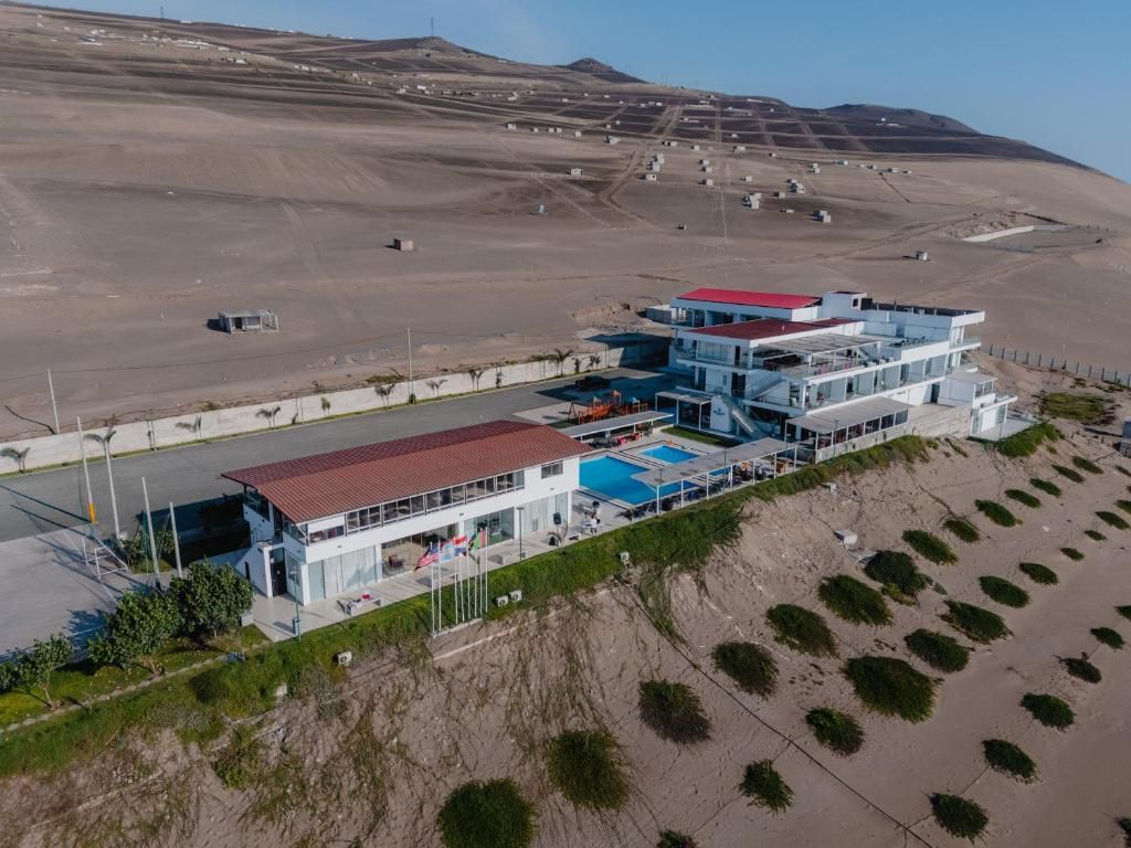 A modern hotel with a pool, located on a hillside with a desert landscape in the background.