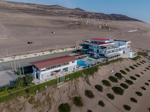 A modern hotel with a pool, located on a hillside with a desert landscape in the background. - Vista a Mar (Aucallama)