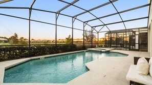Ein Schwimmbad mit Glasabdeckung, ein weißes Outdoor-Sofa und Blick auf die umliegende Landschaft.