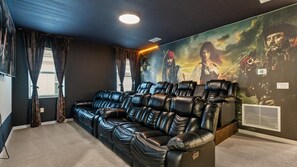 Ein Heimkino mit großer Leinwand, Ledersessel und Wandgemälde.