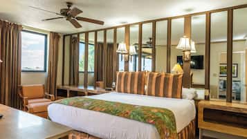 A hotel room with a bed, a desk, a chair, a television, and a ceiling fan.