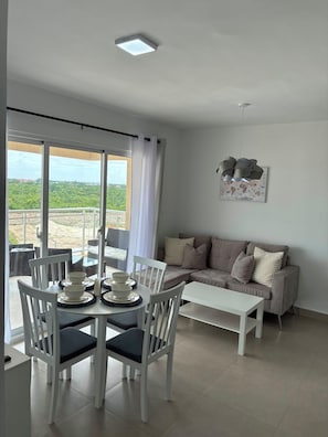 Ein modernes Wohnzimmer mit Essbereich, einer Sofagarnitur und Blick durch große Fenster.