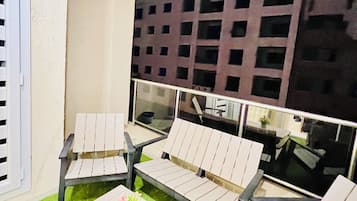 Un área de estar al aire libre con una mesa, sillas, un pequeño arreglo floral y vista a un edificio al fondo.