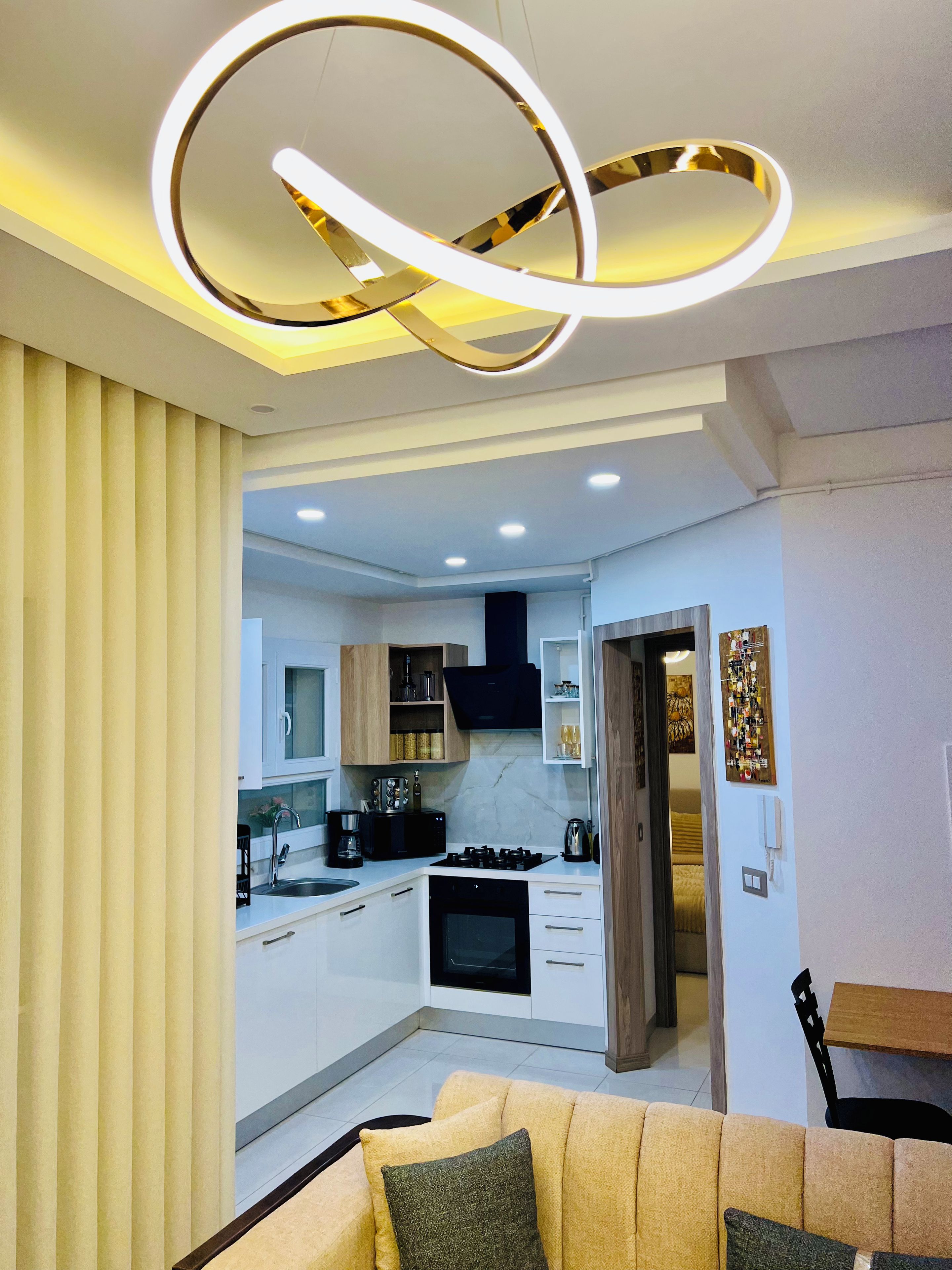 Cocina moderna con electrodomésticos integrados, zona de comedor con sofá y sala de estar con televisor.