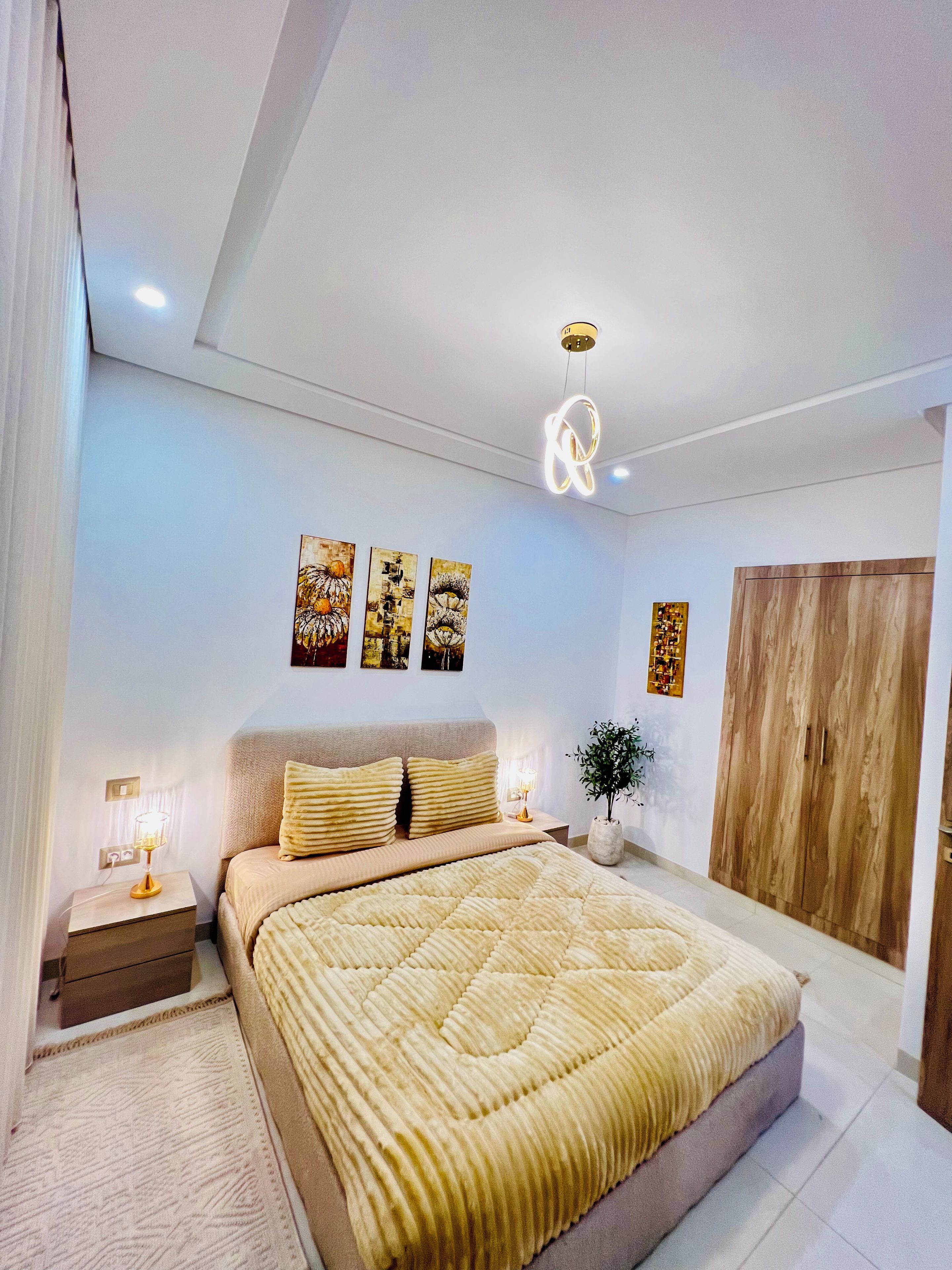 Una camera da letto con un letto, lampade sui comodini, un armadio in legno e decorazioni alle pareti.