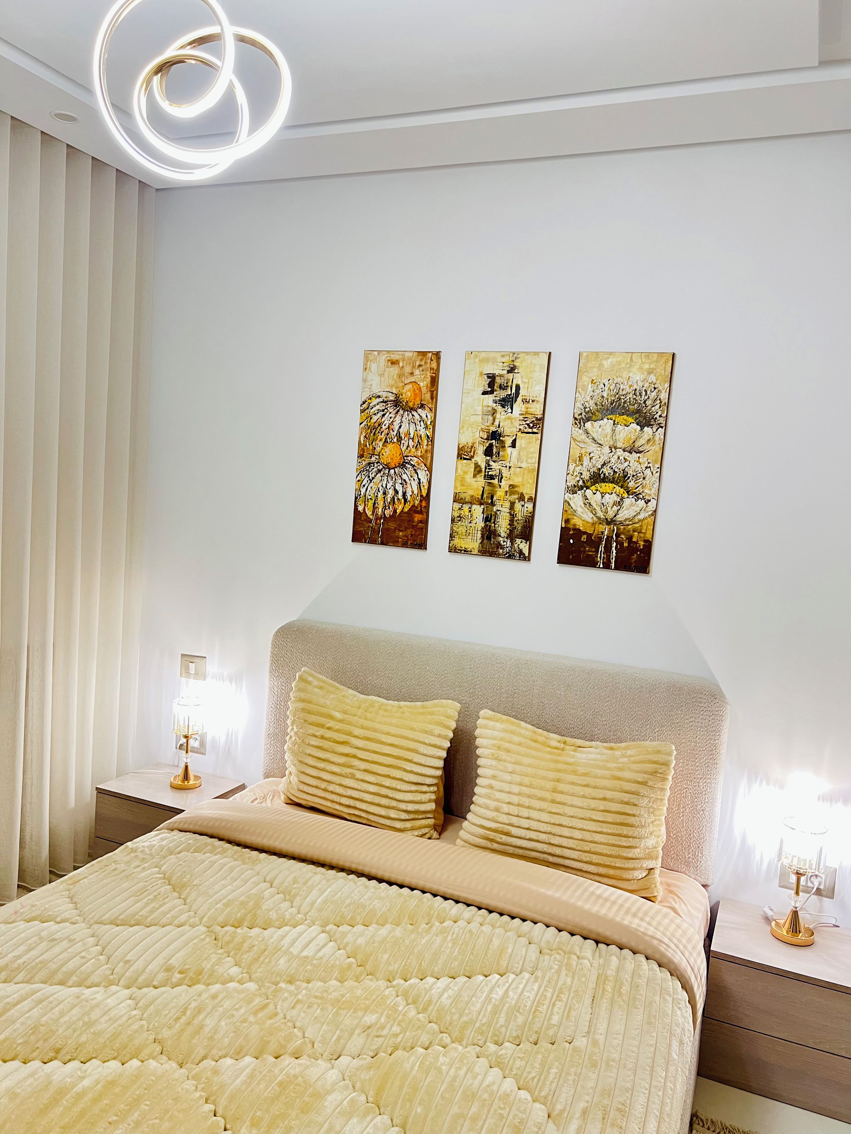Une chambre à coucher avec un lit, des tables de chevet et des œuvres d’art murales.