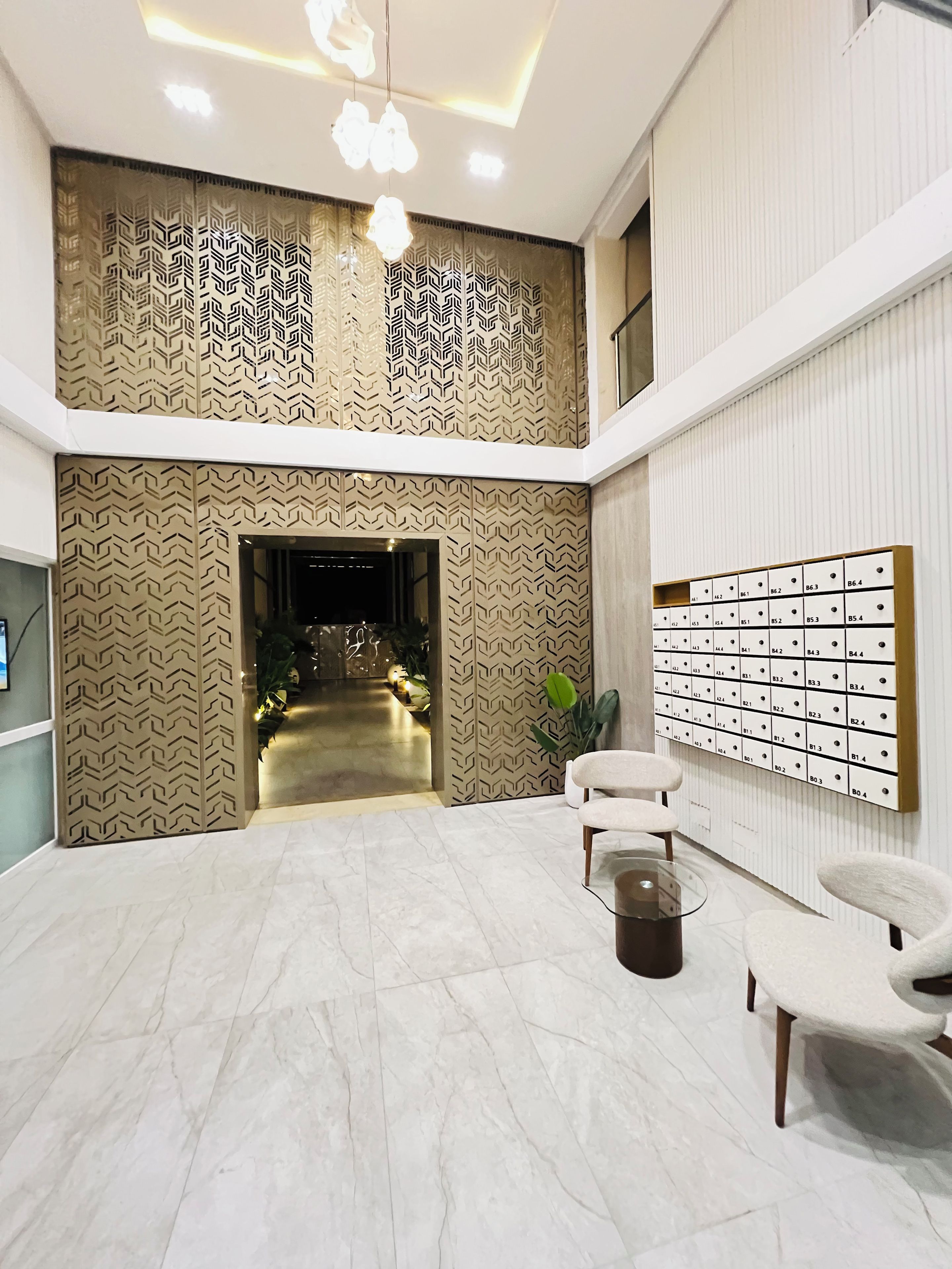 Een moderne lobby met een patroonwand, een zithoek en een wandgemonteerd brievenbussysteem.