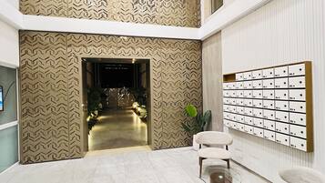 Een moderne lobby met een patroonwand, een zithoek en een wandgemonteerd brievenbussysteem.