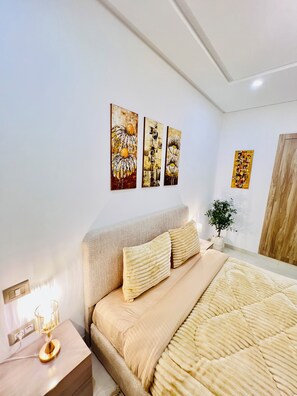 A modern bedroom with a large bed, a nightstand, and wall art.
