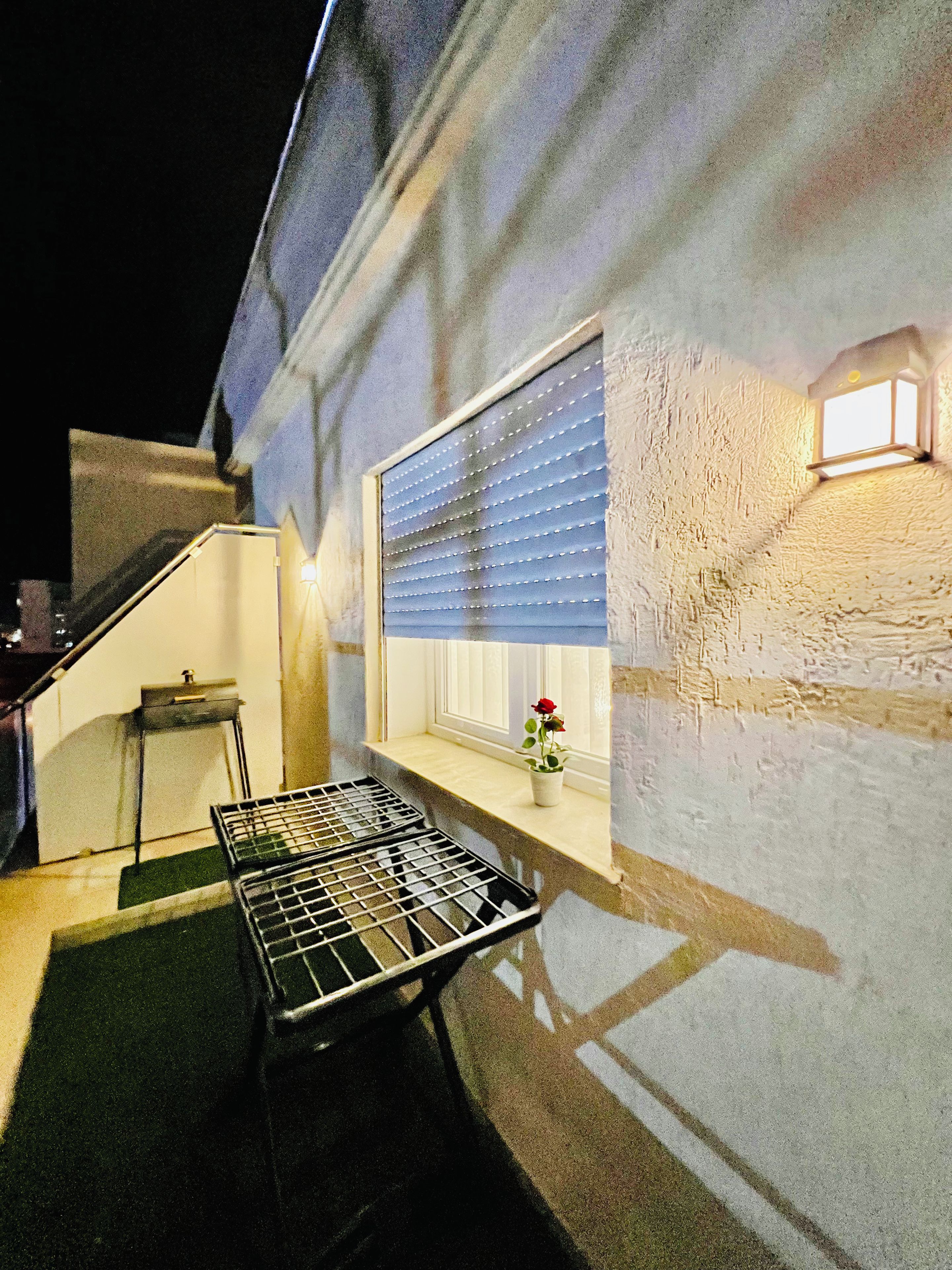 Ein Zimmer mit Fenster, einem kleinen Tisch und einer Bank.