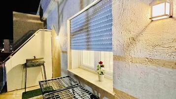 Ein Zimmer mit Fenster, einem kleinen Tisch und einer Bank.