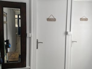 Ein Hotelzimmer mit einer Tür mit der Aufschrift 'Salle de bain' und einer weiteren mit der Aufschrift 'Toilettes', die jeweils ein Badezimmer und eine Toilette kennzeichnen.