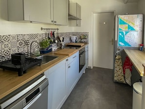 A kitchen with a wooden countertop, a sink, a dishwasher, and a refrigerator with a map.