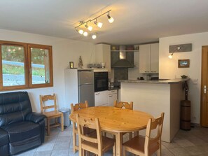 A compact kitchen with a dining area, a black leather sofa, and a wooden dining table. - Charming duplex apartment - 6 guests (Valloire)