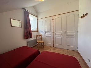 A room with two beds, a chair, a window with curtains, and a wardrobe. - Charming duplex apartment - 6 guests (Valloire)