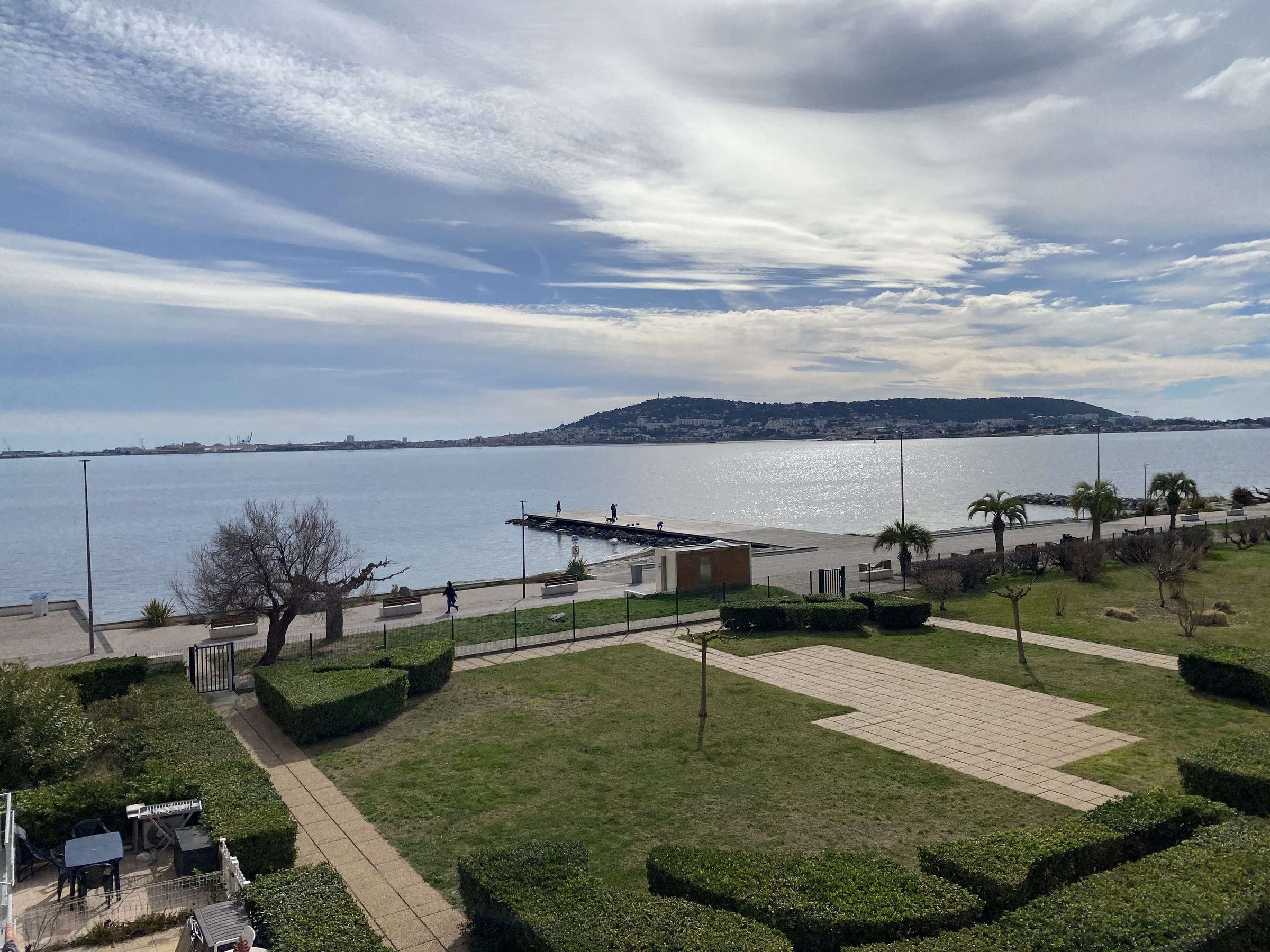 A waterfront park with pathways, benches, and a dock.