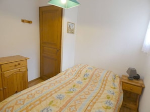 Ein Schlafzimmer mit einem Bett, einem Holzschrank, einem Nachttisch mit Lampe und einer Tür.