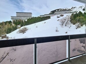 Schneebedeckte Landschaft mit einem modernen Gebäude und einem bewaldeten Hügel.