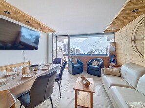Ein modernes Wohnzimmer mit Essbereich, einer Couch und einem an der Wand montierten Fernseher.
