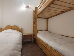 Ein Schlafraum mit Etagenbett, einem Holzkopfteil, einem kleinen Nachttisch und einer Wandleuchte.