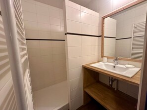 Ein Badezimmer mit weißen Fliesen, einem Holzboden, einem Spiegel und einem Handtuchhalter.